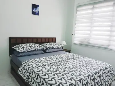 a bedroom with a black and white bed and a window at Yussal Homestay in Simpang Ampat Semanggol