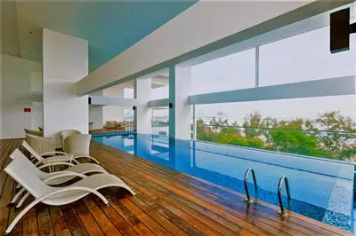 a living room with a swimming pool and chairs at Sunrise Gurney Premium Suite - Gurney Drive in George Town