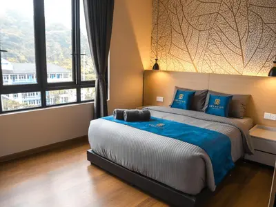 a bedroom with a large bed with blue pillows at Hotel Brynton at Cameron Centrum Mall in Cameron Highlands
