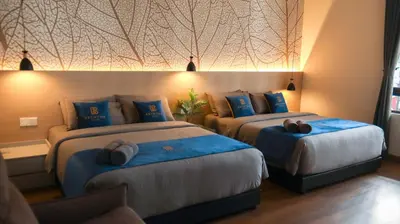 a hotel room with two beds with blue pillows at Hotel Brynton at Cameron Centrum Mall in Cameron Highlands