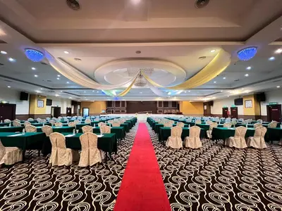 a banquet hall with green tables and chairs and a red carpet at Hotel Taiping Perdana in Taiping