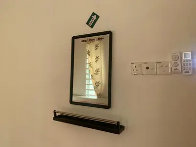 a mirror hanging on a wall with a lightswitch at Damai Homestay in Kampong Jabi
