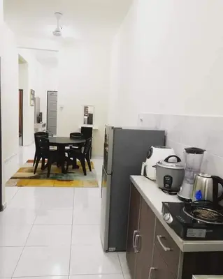 a kitchen with a stove and a table with chairs at Homestay Dorani Sungai Besar in Sungai Besar
