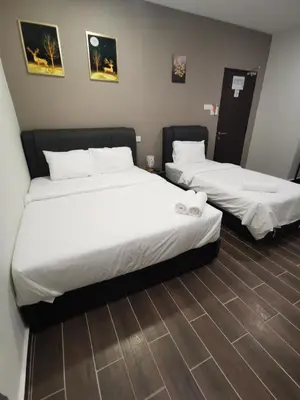two beds in a hotel room with white sheets at Hotel Mutiara in Gua Musang