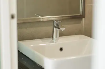 a bathroom sink with a faucet and a mirror at The Palm, 2BR Cityview by WStay @ Tropicana 218 Macalister in George Town
