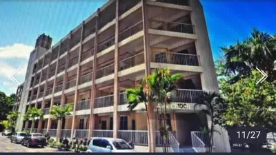 a large building with cars parked in front of it at Batu Feringgi Homestay in Batu Ferringhi
