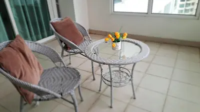 a table with chairs and a vase of flowers on it at Mansion One Entire House 4 QueenBeds - Spacious Balcony Seaview in George Town
