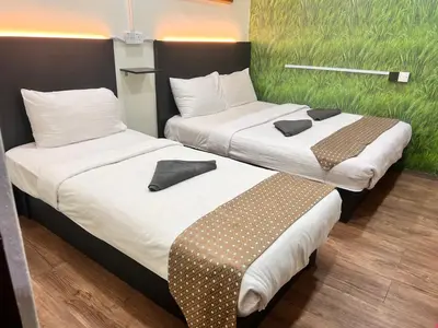 two beds sitting next to each other in a room at Hotel Citra in Brinchang