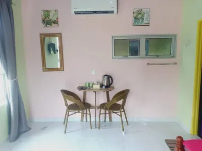 a small table and chairs in a white room at Inap Desa 3 in Kampong Siput