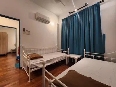 a bedroom with two beds and a blue curtain at Solok Burma Vacation Home @ Gurney Penang in George Town