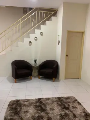 a living room with two chairs and a staircase at ZillQayyim Homestay in Seri Iskandar