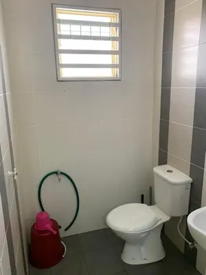 a bathroom with a toilet and a sink and a window at ZillQayyim Homestay in Seri Iskandar