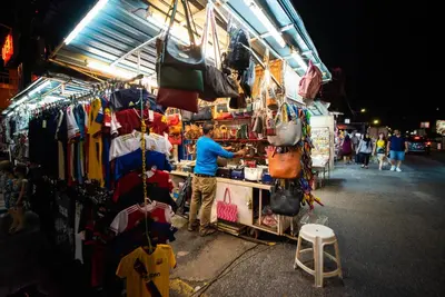 a man standing in front of a clothes stand at a market at Batu Ferringhi Sea View Penthouse Resort Home in Bayan Lepas