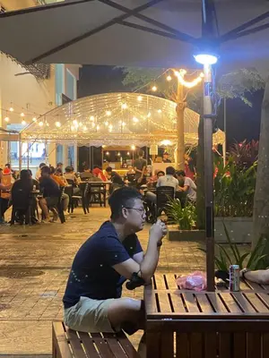 a man sitting on a bench at a restaurant at 6PAX 1 BEDROOM SOHO Near USM SPICE ARENA PANTAI SPECIALIST AIRPORT in Bayan Lepas