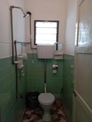 a bathroom with a toilet and a window and green tiles at HEAWOOD GUEST HOUSE Sungai Siput in Sungai Siput