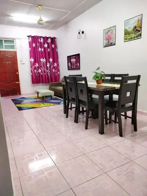 a dining room with a table and chairs and a couch at Rizki Homestay in Nibung Tebal