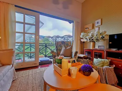 a living room with a table and a large window at Green Hill Apartment in Tanah Rata
