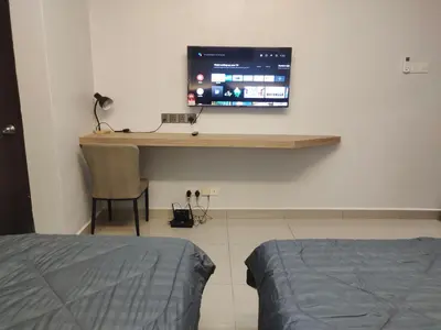 a bedroom with a desk with a television on a wall at Alish Studio Apartment with Pool, Netflix, Wifi in Gua Musang