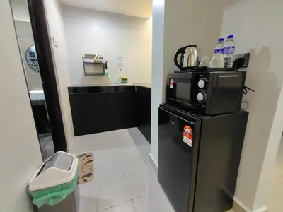 a small kitchen with a black refrigerator and a counter at Alish Studio Apartment with Pool, Netflix, Wifi in Gua Musang
