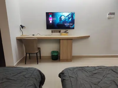 a room with a desk with a tv on a wall at Alish Studio Apartment with Pool, Netflix, Wifi in Gua Musang