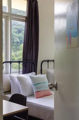 a bed with pillows sitting in front of a window at EE's Surfer's House - Seaview, 3 min walk to beach in Batu Ferringhi