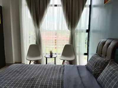 a bedroom with a bed and two chairs and a large window at Armada Sweet Homestay in Gua Musang