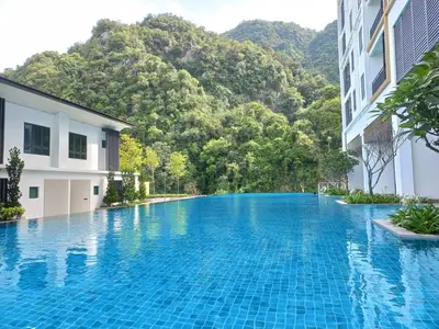 a swimming pool in front of a building with a mountain at Sunway Onsen Studio @ Lost World of Tambun in Ipoh