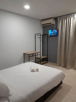 a bedroom with a white bed and a television at The Great Hotel in Ipoh