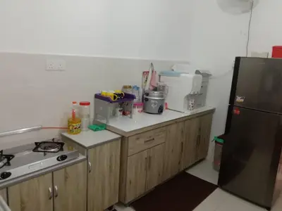 a kitchen with wooden cabinets and a black refrigerator at AWANA HOMESTAY in Sungai Petani