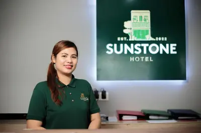a woman sitting at a table in a room at Sunstone Hotel in George Town