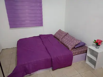 a purple bed in a white room with a purple blanket at Purple Pool Villa in Kampong Batu Dua Puloh Tiga