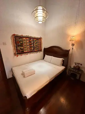 a bedroom with a bed with white sheets and a lamp at The White Horse in Cameron Highlands