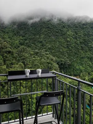 a table and two chairs on a balcony with a mountain at Cozy Suite with 270 Degree Mountain and Theme Park Views in Ipoh