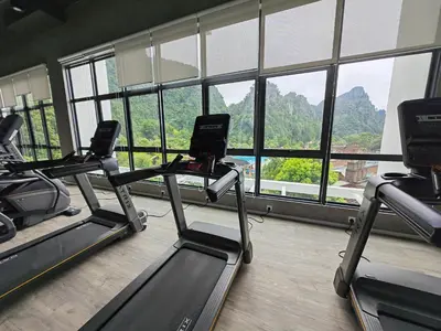 a gym with three treadmills in front of a window at Cozy Suite with 270 Degree Mountain and Theme Park Views in Ipoh
