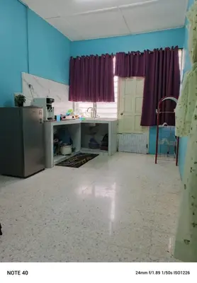 a kitchen with a refrigerator and a window with purple curtains at Hazaff Homestay in Sungai Petani