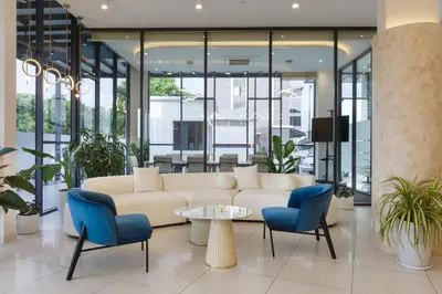 a living room with a white couch and blue chairs at Wellesley Hotel in Simpang Ampat