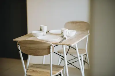 a wooden table with two chairs and plates and cups at The WHITE, 2BR Cityview by WStay @ Tropicana 218 Macalister in George Town