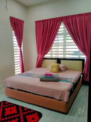 a bedroom with a bed with pink curtains and a window at Homestay Haji Din Tronoh Perak in Teronoh