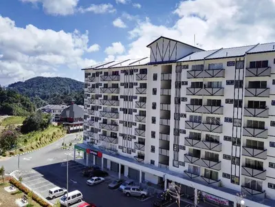 a large white building with cars parked in a parking lot at Cameron Lovely Home 3 Rooms in Tanah Rata
