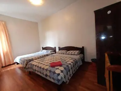 a bedroom with two beds in a room with wooden floors at Aspen Holiday Apartment in Tanah Rata
