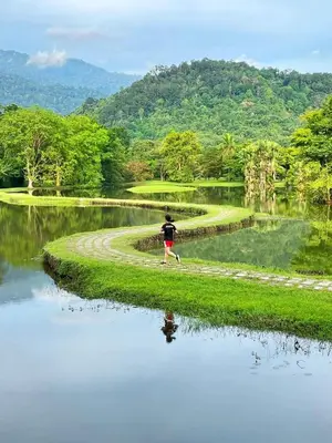 a person walking on a dirt road next to a body of water at Raintown inn taiping in Taiping
