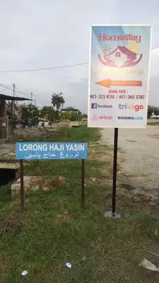 two signs sitting in the grass next to a road at Homestay Embah Ros & Embah Lek in Hutan Melintang