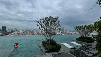 a person in a pool of water with a city in the background at Beacon Executive Suites #CozyFamilyStay #RoofTopPool #13 in George Town