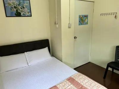 a bedroom with a bed and a door and a chair at De Cameron Guest House in Tanah Rata