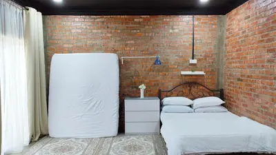 two beds in a room with a brick wall at Studio Amani 1 Permatang Pauh in Permatang Pauh