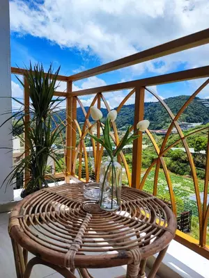 a wicker rattan table on a balcony with a view at Muji Homestay @ The Retreat, Cameron Highlands in Cameron Highlands