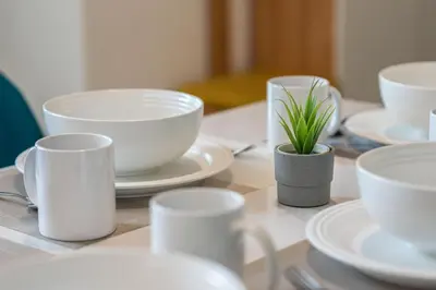 a table with white cups and a potted plant on it at De Luma-Metropol in Bukit Mertajam