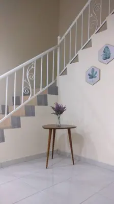 a vase of flowers on a table next to a staircase at Setia Residen Semi-D two half storey 5 Bedrooms unlimited wifi in Sitiawan