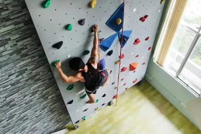 a man climbing a climbing wall in a room at Private Rock Climb at The CEO Penang in Bayan Lepas