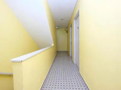 a hallway with a yellow wall and a white staircase at Ar Rayyan Hotel in Tanah Rata